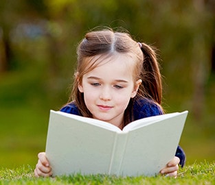 girl reading book in grass