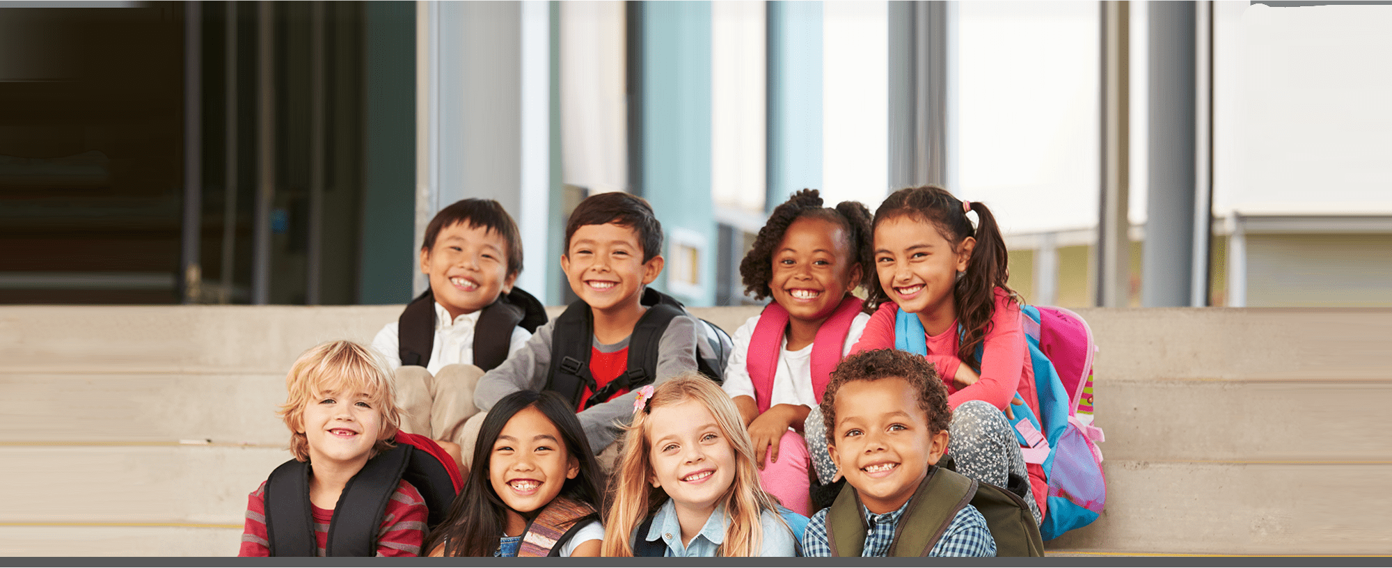 group of students sitting on steps with backpacks